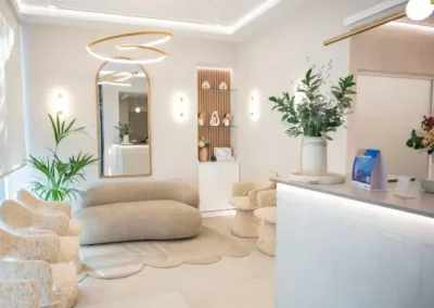 Sala de espera premium de Lúmina Clinic en Madrid con sofás y sillones en tonos beige, espejo arqueado e iluminación cálida.